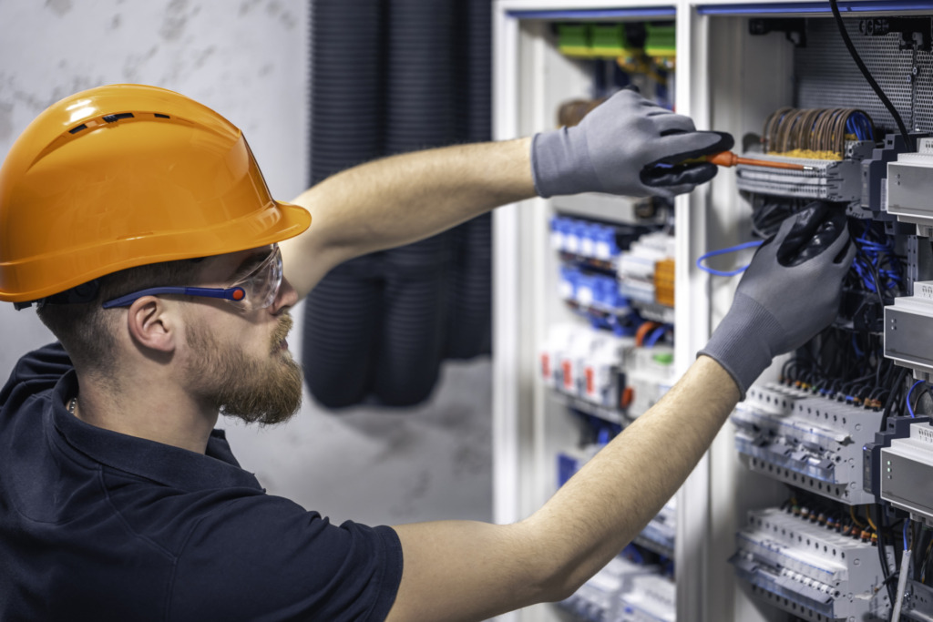 Male electrician working in a switchboard with fuses.
