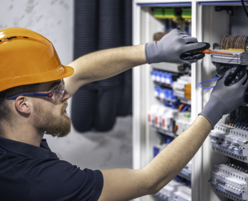 Male electrician working in a switchboard with fuses.